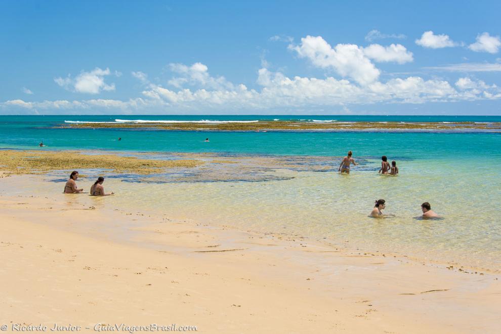 Imagem de famílias aproveintado o mar calmo da Praia de Taipu de Fora.